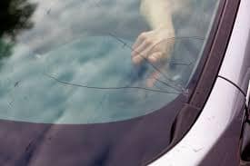 Close-up of a car windshield with cracks and chips requiring professional auto glass repair.